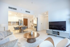 A modern living room with a flat-screen TV, a dining area, and a kitchen. - Bloomfields Cozy 1br Apt Town (Dubai)