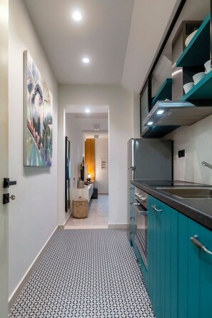 A modern kitchen with teal cabinets, a stainless steel refrigerator, and a patterned floor. - Dirapera Port Suite- Proximity to Corfu's Port & City (Corfu)