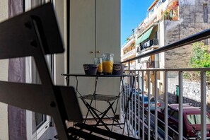 Un balcón con un tendedero de metal que sostiene dos vasos de jugo de naranja y una pequeña mesa.