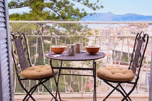 Un balcon avec deux chaises en métal et une table, entouré d’une clôture en treillis blanc.