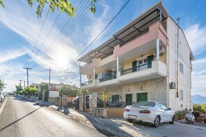 A two-story residential building with a balcony on the upper floor, a car parked in front, and a clear sky. - Seaview Portside apartment (Corfu)