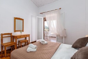 A bedroom with a bed, a wooden desk, a chair, a mirror, and a window with sheer curtains. - Dany Apartment – First Floor with Sea View (QWQF+J59 Kassiopi, Greece)