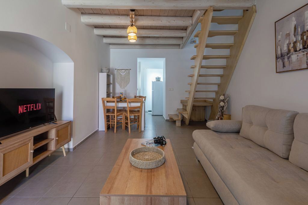 A living room with a TV, wooden coffee table, sofa, staircase, and dining area.