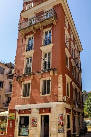 Un edifici vermell amb nombroses finestres i balcons, que inclou un restaurant anomenat "Palatte Brunch Plants" a la planta baixa.