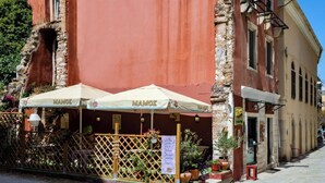 A café with outdoor seating, a lattice fence, and a sign reading "MAMOZ". - Scala Nostra Apartment (Corfu)