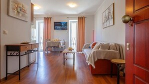 A living room with a sofa, a dining table, and a TV. - Scala Nostra Apartment (Corfu)