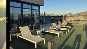 A rooftop lounge with sun loungers and a glass building. -  Luxury studio w/ rooftop infinity pool & TJ sunset views Cosmopolitan tower!…. (Tijuana)