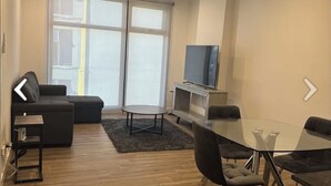 A modern living room with a sofa, a glass dining table, and a TV. -  Luxury studio w/ rooftop infinity pool & TJ sunset views Cosmopolitan tower!…. (Tijuana)
