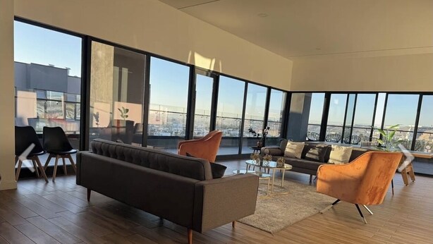 A spacious living room with a large window offering a city view, a sofa, two armchairs, and a coffee table. -  Luxury studio w/ rooftop infinity pool & TJ sunset views Cosmopolitan tower!…. (Tijuana)