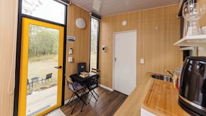A compact kitchen with a dining area, a view through a glass door, and a small outdoor seating area.