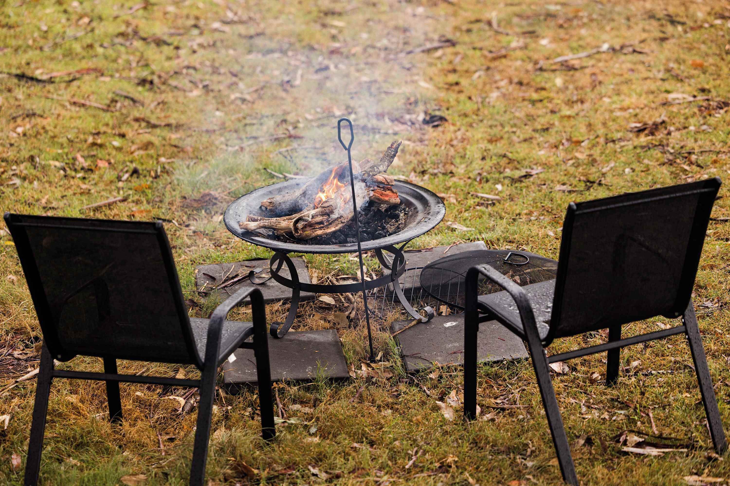 Une table en métal avec un foyer au centre, entourée de deux chaises.