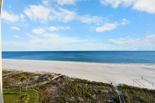 A beach view with a clear sky, sandy beach, and a pathway leading to the water.