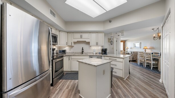 A modern kitchen with stainless steel appliances, a central island, and a dining area with a table and chairs. - Bluewater 902 (Orange Beach)