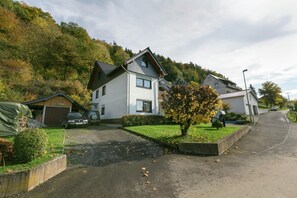 Eine Wohnstraße mit Häusern, einem Auto und einem Baum.