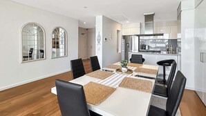 A modern kitchen with white cabinets, a stainless steel range hood, and a built-in oven. - Stylish Apartment Near Mandurah’s Best Spots (Mandurah)