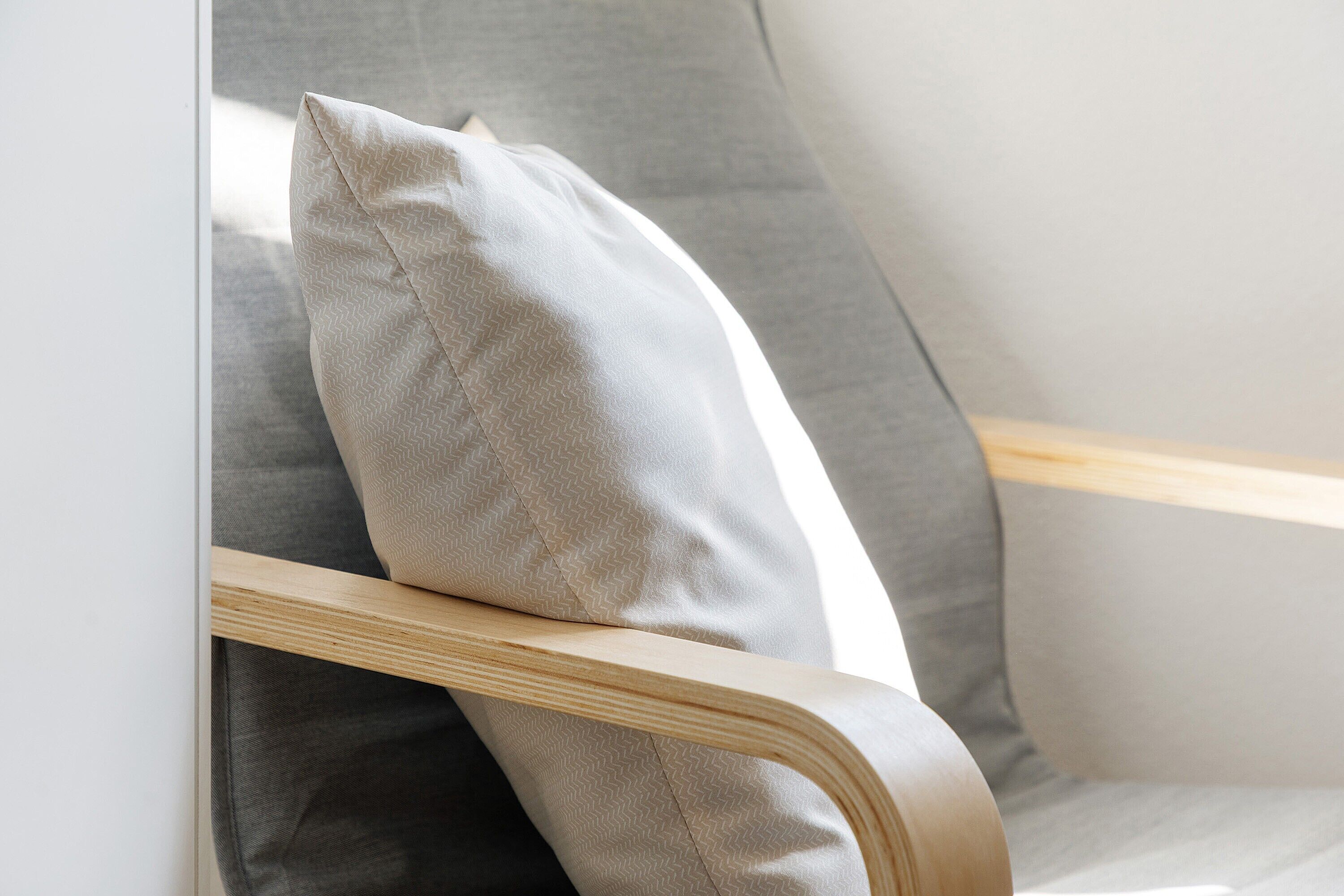 Une chaise avec une structure en bois et un coussin gris.