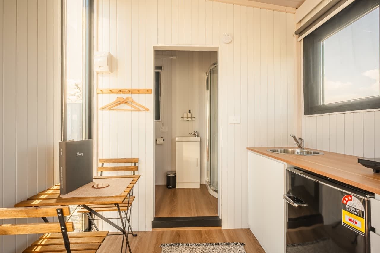 A compact kitchen with a wooden table, a sink, and a refrigerator.