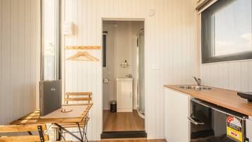 A compact kitchen with a wooden table, a sink, and a refrigerator.