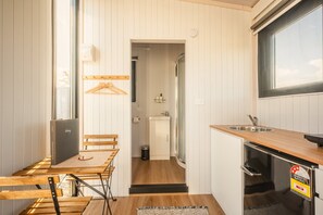 A compact kitchen with a wooden table, a sink, and a refrigerator. - Rimu View 4 by Tiny Away (Ruatapu)