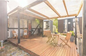 A covered outdoor area with wooden flooring, seating, and a sheltered entrance. - Rimu View 4 by Tiny Away (Ruatapu)