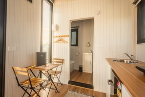 A compact kitchen with a dining area, a sink, and a small refrigerator. - Rimu View 4 by Tiny Away (Ruatapu)