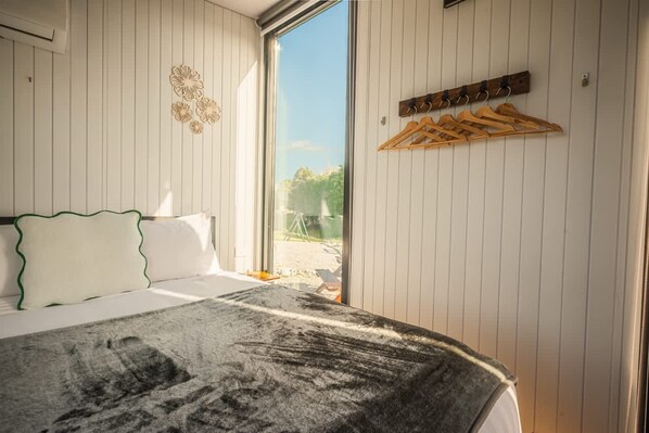 A bedroom with a bed, a window, and a wall-mounted clothing rack.