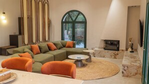 Ein modernes Wohnzimmer mit einem Ecksofa, einem runden Couchtisch und einem großen Bogenfenster.