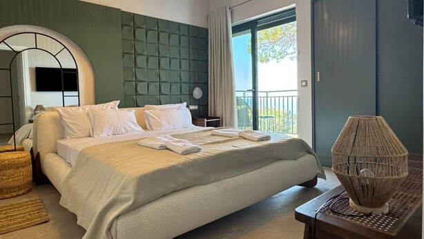 Ein modernes Hotelzimmer mit einem großen Bett, einem Balkon mit Blick und einem einzigartigen gewobenen Nachttisch.
