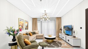 Un salon moderne avec un canapé d’angle, une table basse ronde et un téléviseur posé sur un meuble.
