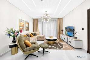 A modern living room with a sectional sofa, a round coffee table, and a TV on a cabinet. - 1BR Royal Amwaj Private Beach& Burj view (Dubai)