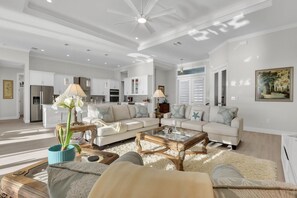 Ein großzügiges Wohnzimmer mit einer großen Couch, einem Couchtisch und einem Essbereich mit einer Deckenleuchte.