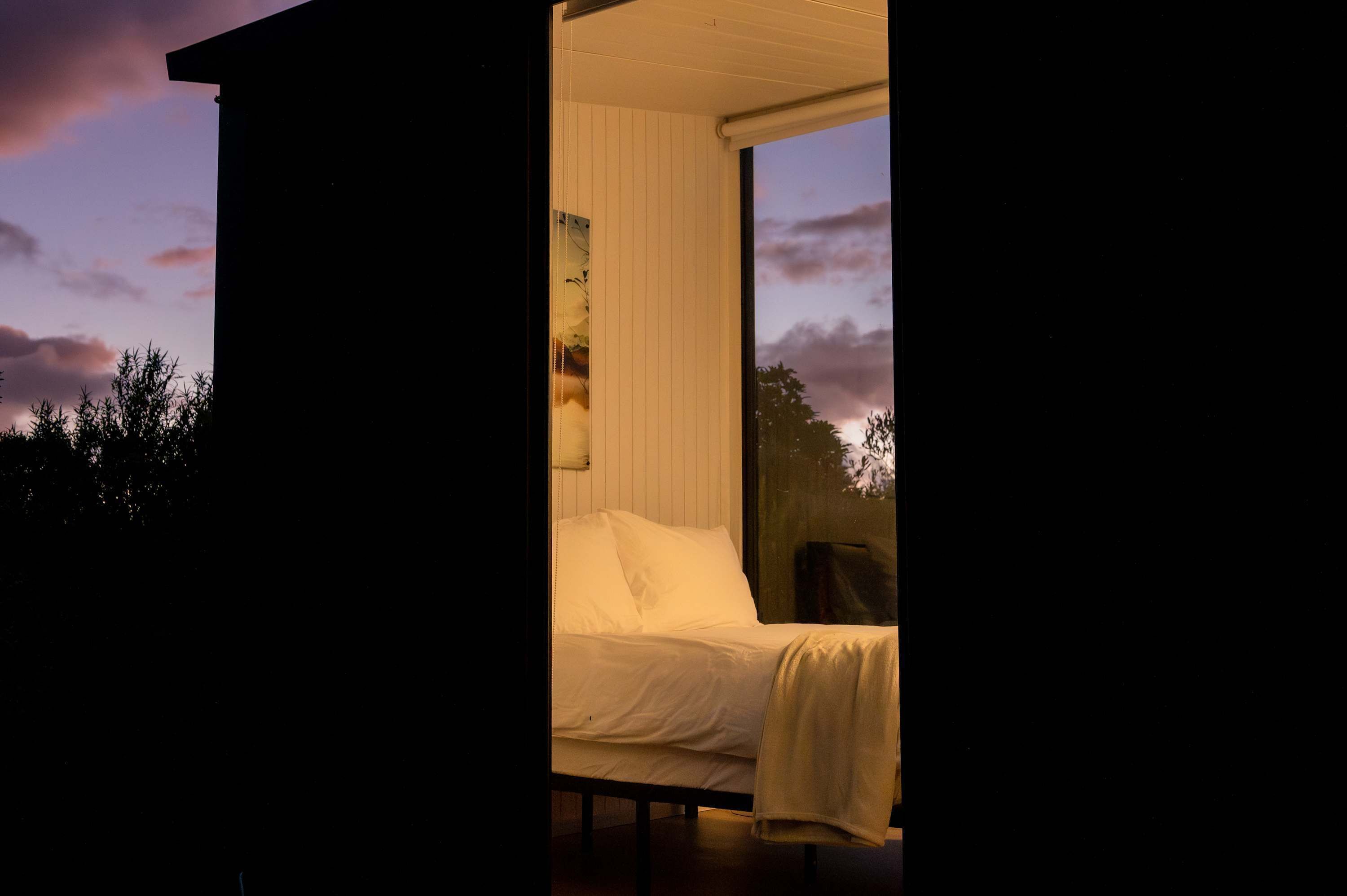 Un dormitorio con cama, ventana y vista al cielo.