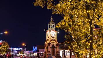 A clock tower with a clock face, surrounded by illuminated trees and buildings.