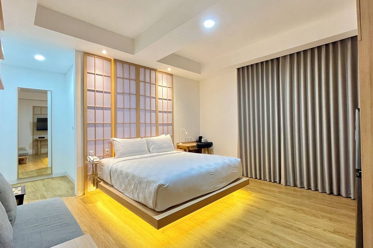 A modern bedroom with a bed, bedside table, and a mirror.