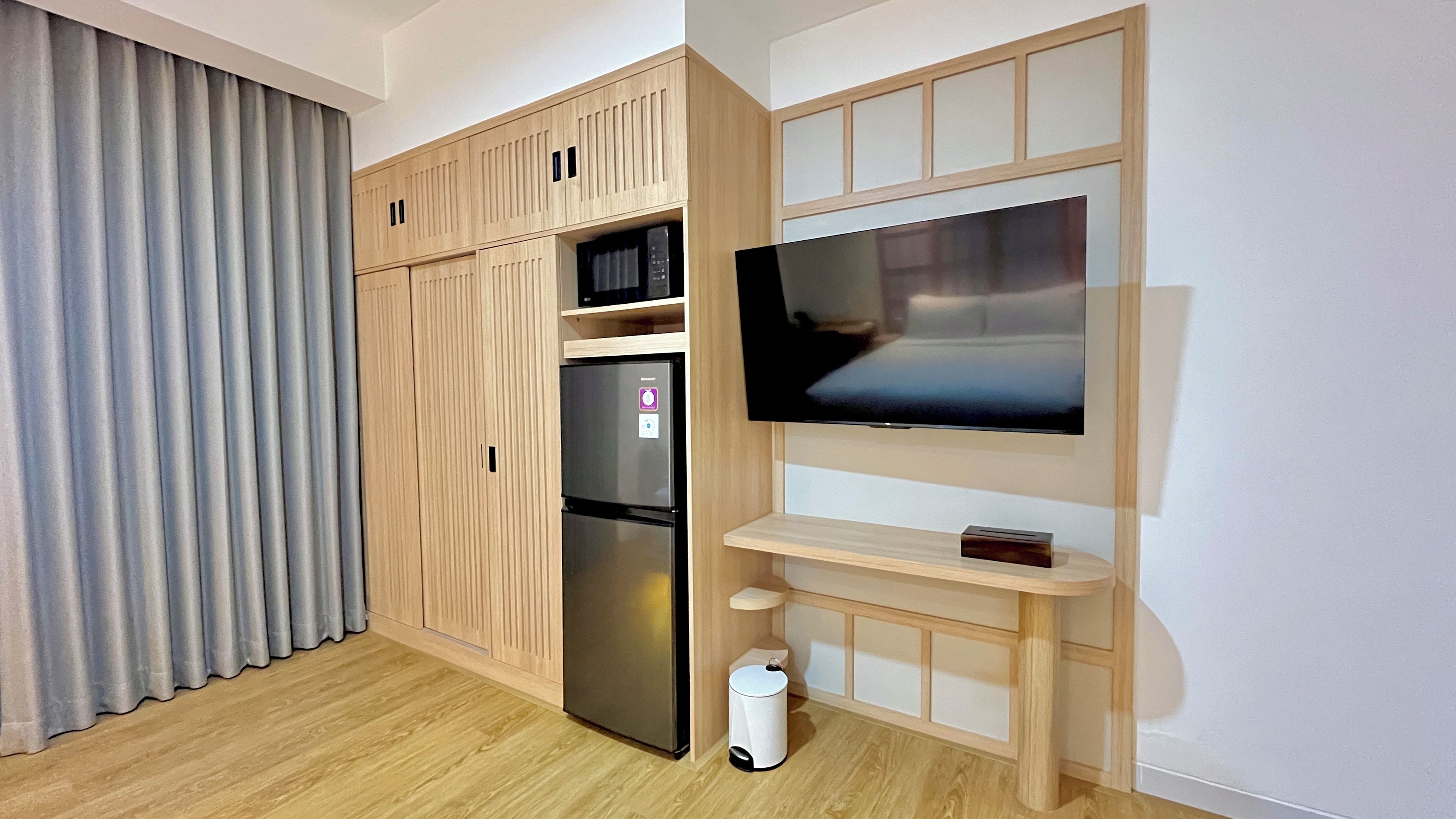 A modern room with a built-in TV, a refrigerator, and a trash bin.