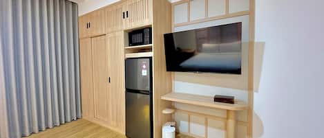A modern room with a built-in TV, a refrigerator, and a trash bin.