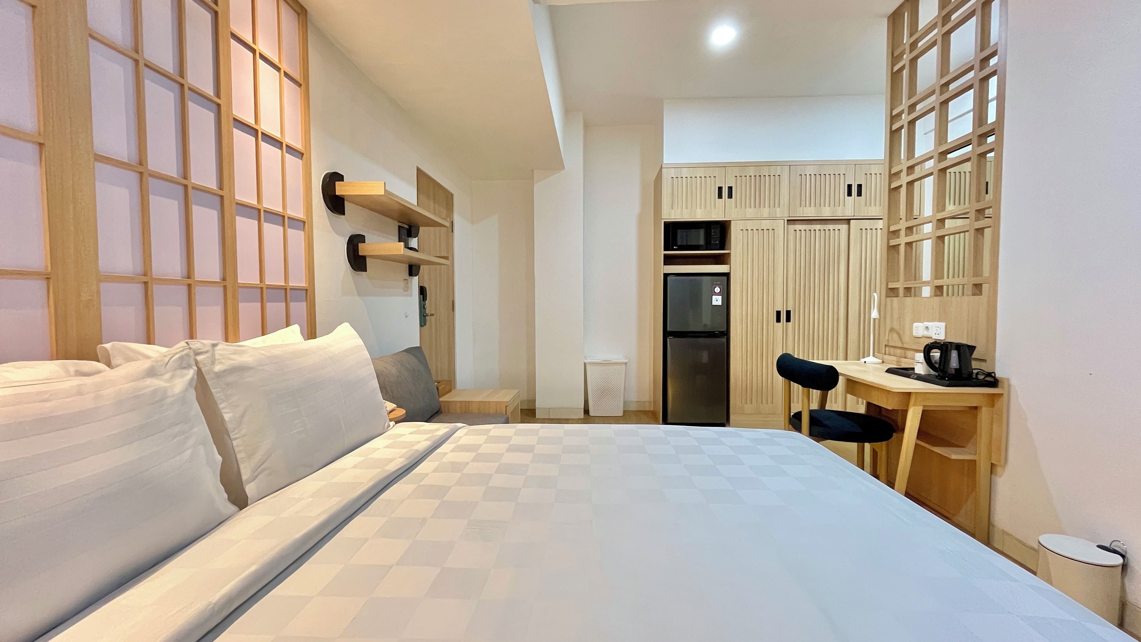Una habitación de hotel con cama, escritorio, silla, refrigerador y microondas.