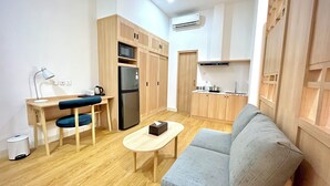 A compact living space with a kitchenette, a sofa, a small table, and a desk with a chair. - Jambuluwuk Mansion Adityawarman (Jakarta)