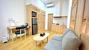 A compact living space with a kitchenette, a sofa, a small table, and a desk with a chair. - Jambuluwuk Mansion Adityawarman (Jakarta)