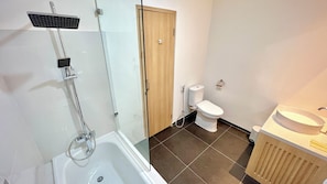 Et badeværelse med brusebad, toilet og håndvask.