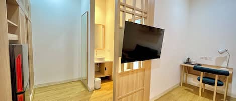 Ein modernes Zimmer mit Fernseher, Schreibtisch und Stuhl.
