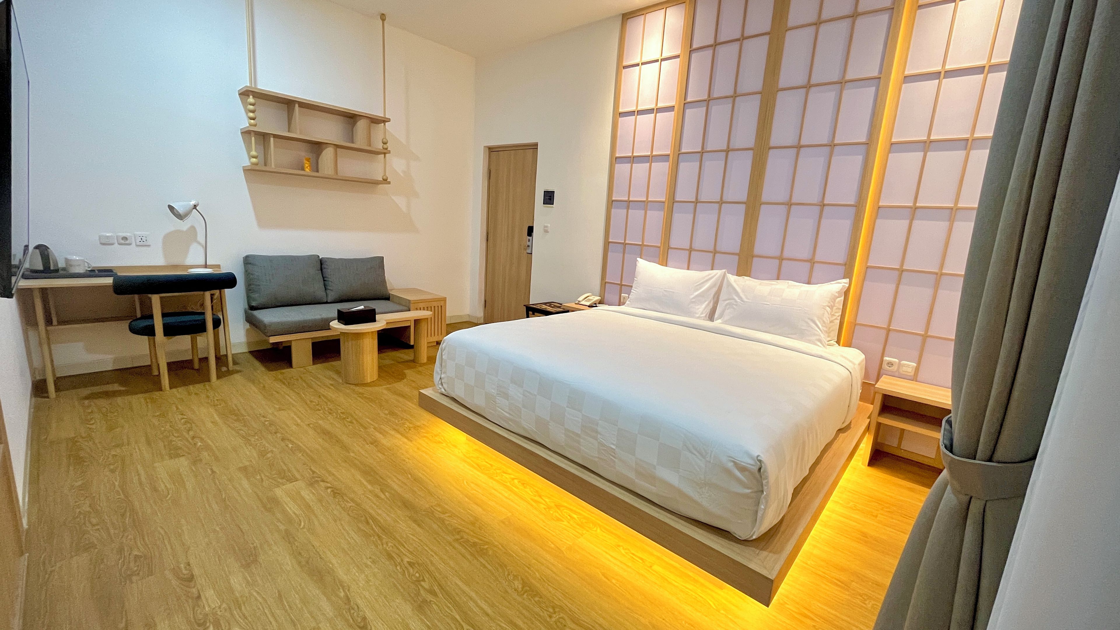 Ein Hotelzimmer mit einem Bett, einem Schreibtisch mit Stuhl, einer Couch und einem Fenster mit Aussicht.