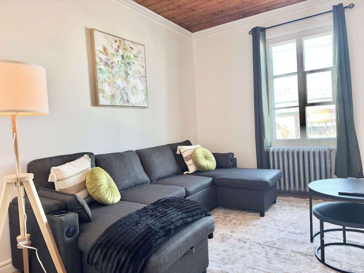 A modern living room with a sectional sofa, a small round table, and a floor lamp.