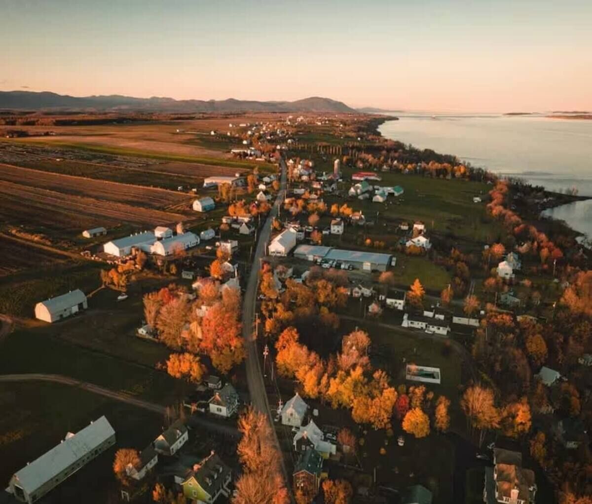 Luchtbeeld van een klein stadje met huizen, schuren en een rivier.