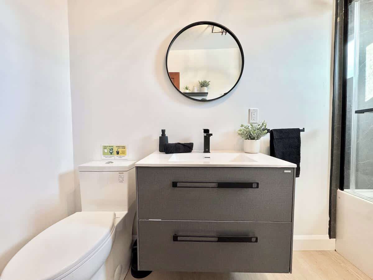 Une salle de bain moderne équipée de toilettes, d’un lavabo avec un miroir et d’un porte-serviettes.