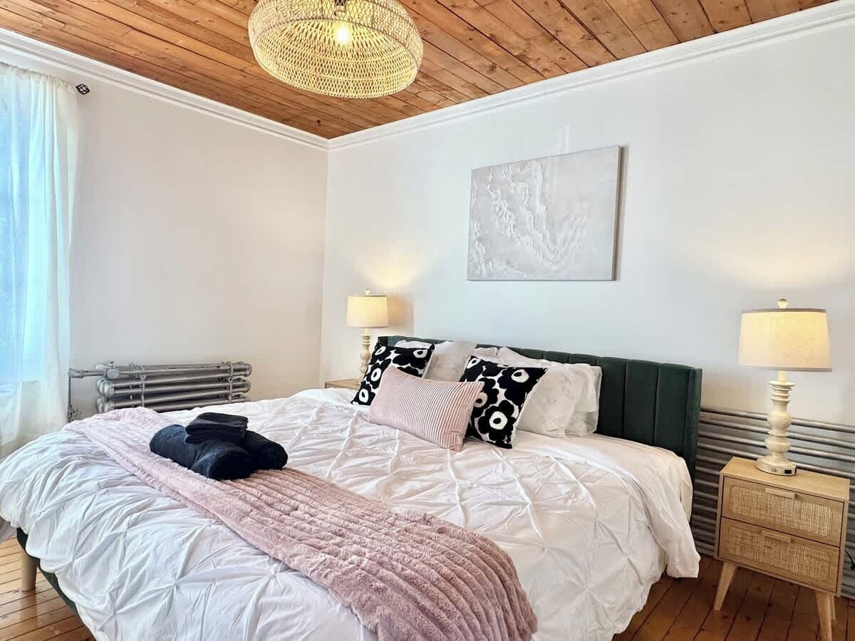 A bedroom with a bed, a radiator, a bedside table, and a lamp.