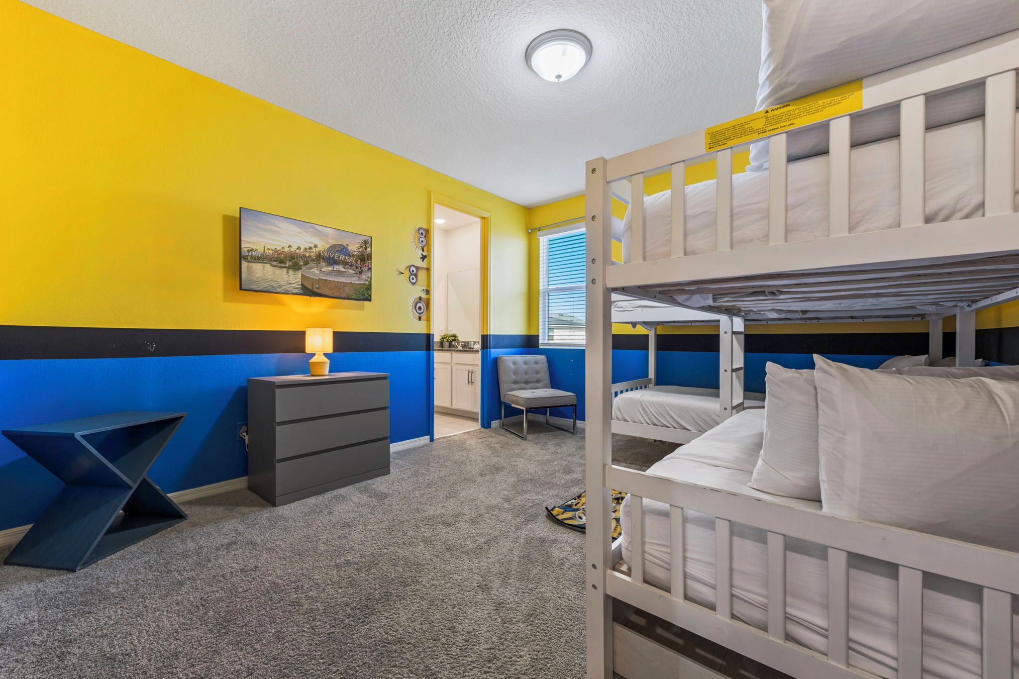 Ein Schlafraum mit Etagenbetten, Schreibtisch, Stuhl und einem Bild an der Wand.