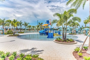 A children's play area with a slide and climbing structures, surrounded by palm trees and lounge chairs. - 2011 Fleming Mist Place (Kissimmee)