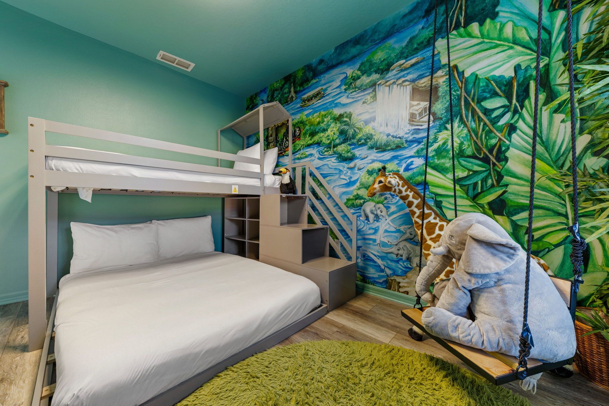 Una cama litera con colchón blanco, una alfombra verde y un mural con una jirafa y un elefante.
