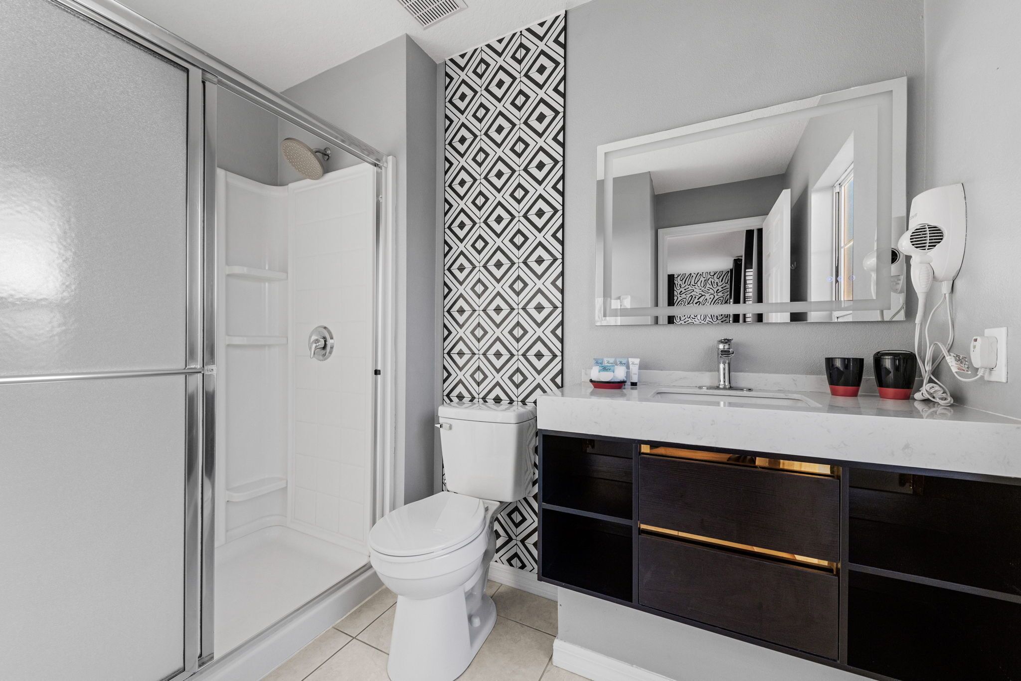 A modern bathroom with a shower, toilet, vanity, and a large mirror.